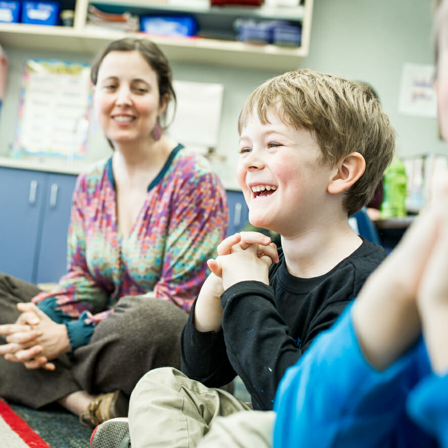 Laughing boy sits on classroom floor