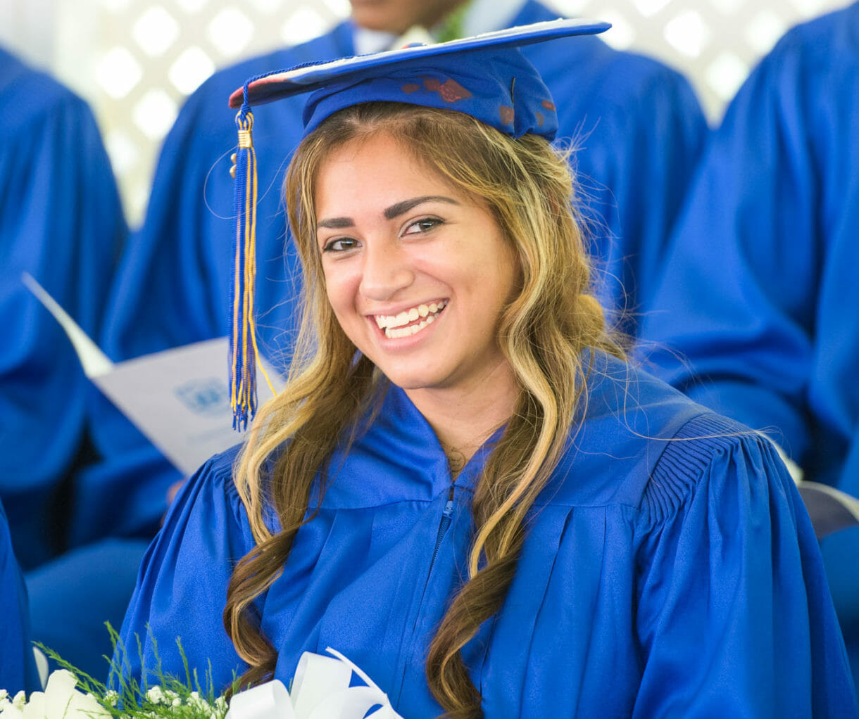 Smiling girl sits in row at graduation