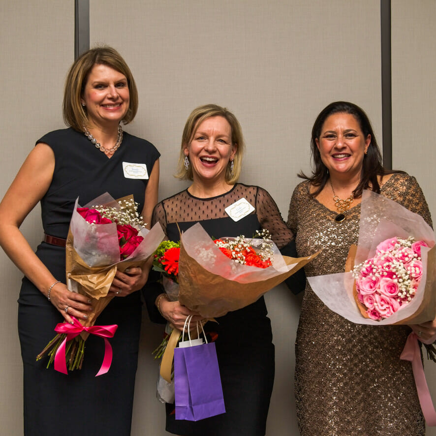 Three women hold flower bouquets