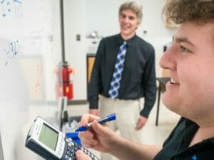 Smiling upper school student writes on whiteboard