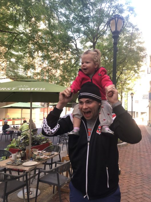 Josh Hicks, History teacher at McLean School, smiles at camera at an outdoor restaurant